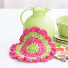 a crocheted dishcloth and pot holder on a table with a green pitcher