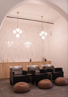 a room with chairs, stools and lights hanging from the ceiling in front of a mirror