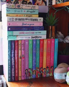 a stack of children's books sitting on top of a wooden shelf next to a potted plant