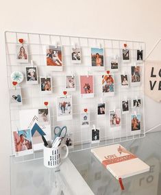 a glass table topped with pictures and a coffee cup next to a wall mounted memo board