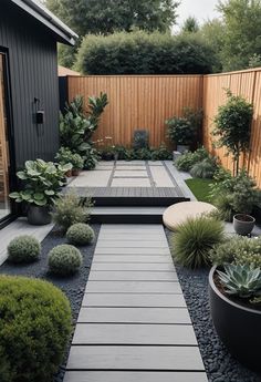 an outdoor garden with gravel, plants and wooden walkway leading to a small patio area