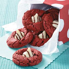 red velvet cookies with white chocolate drizzles in a paper bag on a blue tablecloth