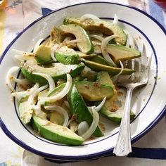 a white plate topped with sliced up vegetables and a fork on top of a blue and white table cloth