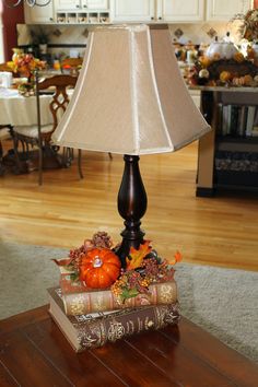 a lamp sitting on top of a table next to an open book and pumpkins