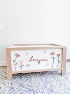 a wooden box with flowers painted on the side and words that spell it's happy