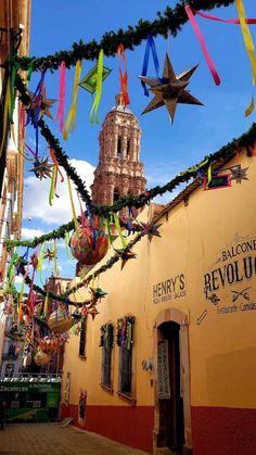 many colorful streamers are hanging from the side of a building with a clock tower in the background