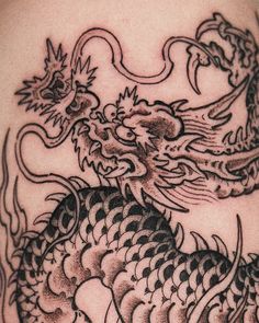 a close up of a dragon tattoo on the back of a person's shoulder