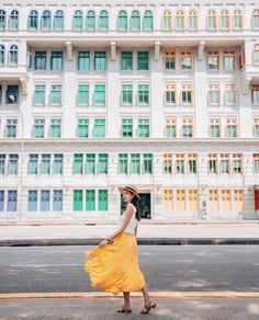 a woman is walking down the street in front of a large building with many windows