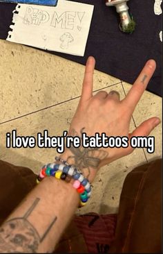 someone is holding their hand up to say i love they're tattoos omg