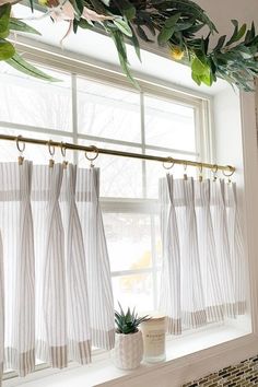 a window with white curtains and green plants hanging from it's rodulage