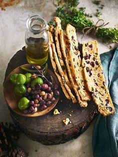 olives and pita bread are on a wooden plate next to a jar of olive oil