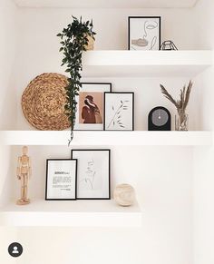 three white shelves with pictures and plants on them