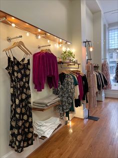 a clothing store with clothes hanging on racks and lights above the rack, along with other items