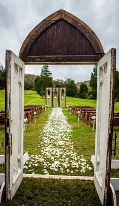 an open door leading to a ceremony with white flowers on the grass in front of it