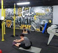 some people are doing exercises in a gym with graffiti on the wall behind them,