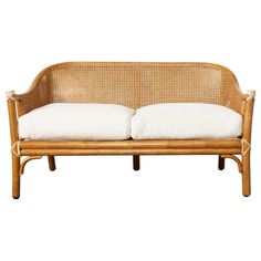 a wicker couch with two white pillows on it's back and arms, in front of a white background