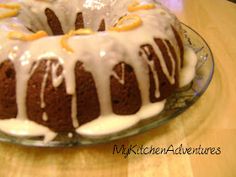 a bundt cake with icing and oranges on top sitting on a glass plate