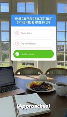 a laptop computer sitting on top of a wooden table next to a plate of food