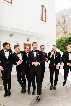 a group of men in tuxedos standing next to each other near a building