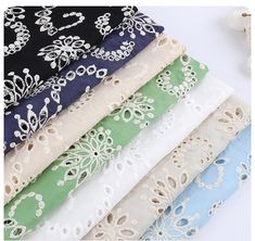 several different colors and designs of laces on white fabric, with flowers in the background