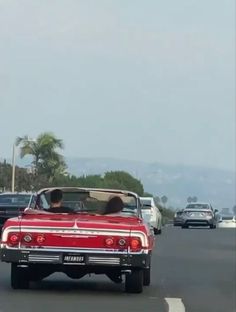 an old red car driving down the road