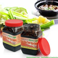 two jars of chili sauce sitting on top of a table next to vegetables and other foods