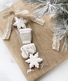 some cookies are sitting on a cutting board next to a christmas tree and pine cones