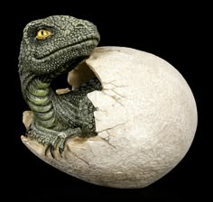 an egg shell with a toy dinosaur in it's mouth and the eggshell is cracked open