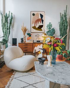 a living room filled with furniture and lots of potted plants on top of a table