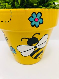 a yellow flower pot with a bee painted on it