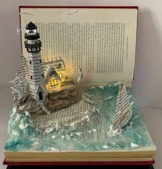 an open book with a lighthouse and boat on it's pages in the shape of a book