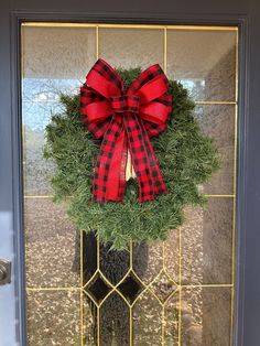 a wreath with a red bow hanging on the front door