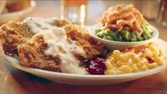 a white plate topped with fried chicken and macaroni and cheese covered in gravy