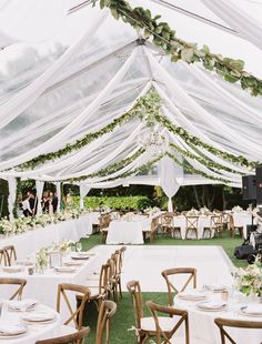 the inside of a tent with tables and chairs set up for an outdoor wedding reception