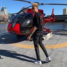 a man standing in front of a red helicopter