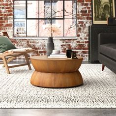 a living room filled with furniture and a brick wall in the background, there is a coffee table surrounded by two chairs