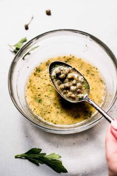 a spoon with some food in it on top of a glass bowl filled with soup