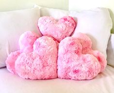 two pink teddy bears sitting on top of a white bed next to pillows and pillows