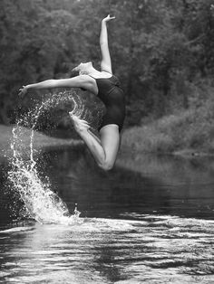 a woman jumping in the air while wearing a bathing suit and flips her feet into the water