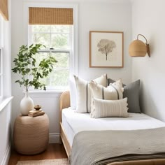 a bedroom with white walls and wooden flooring is decorated in neutral tones, including pillows