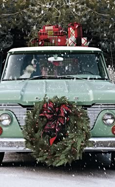 an old truck with a christmas wreath on the front window and presents in the back