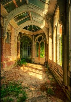 an abandoned building with lots of windows and ivy growing on the walls, along with stone walkways