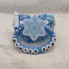 a baby's winter bracelet with a snowflake on it and the words winter baby spelled in white letters