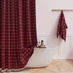 a bath tub sitting next to a red shower curtain