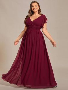 a woman in a long burgundy dress posing for the camera with her hands on her hips