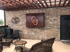 an outdoor patio area with wicker furniture and brick walls, surrounded by potted plants