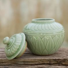 a green vase sitting on top of a wooden table next to a cookie jar and lid