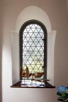 a vase with flowers in it sitting next to a window that has a stained glass design