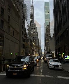 cars are parked on the street in front of tall buildings and skyscrapers at dusk