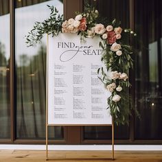 a sign with flowers and greenery on it in front of a window that says find the seat